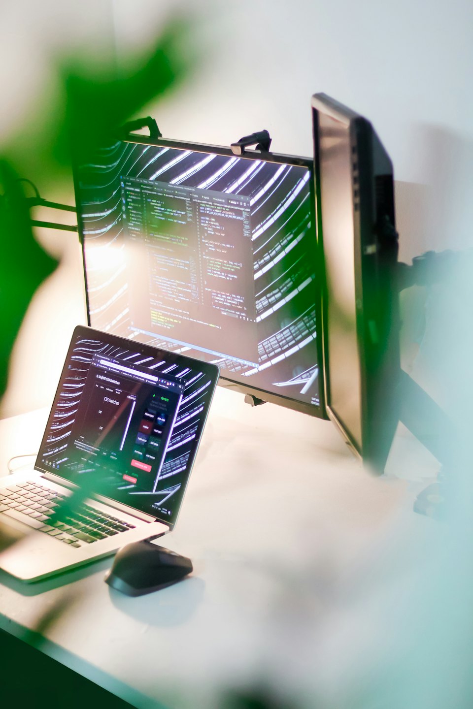 Laptop e doppio monitor con codice su una scrivania.