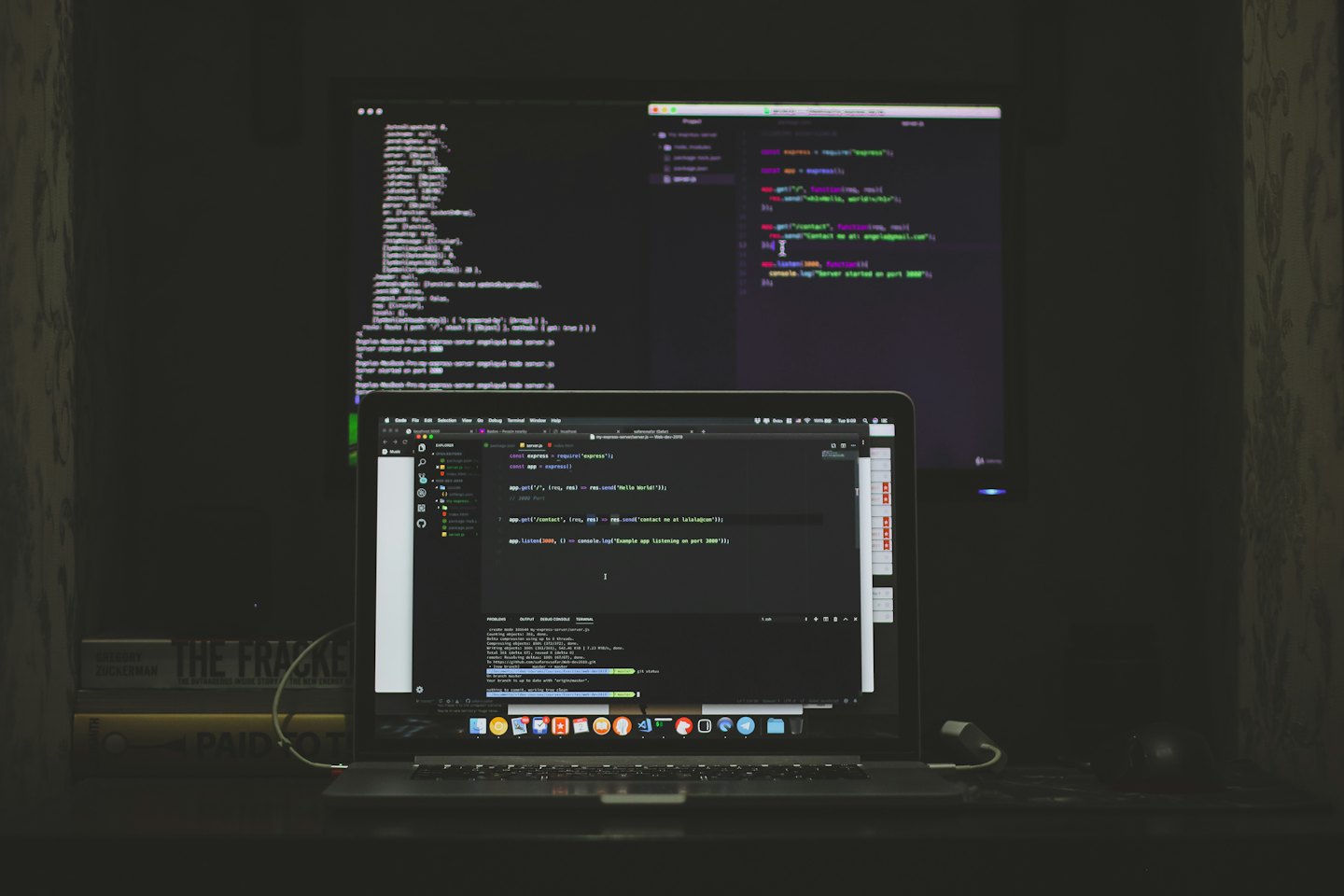Laptop e monitor esterno con codice su una scrivania.