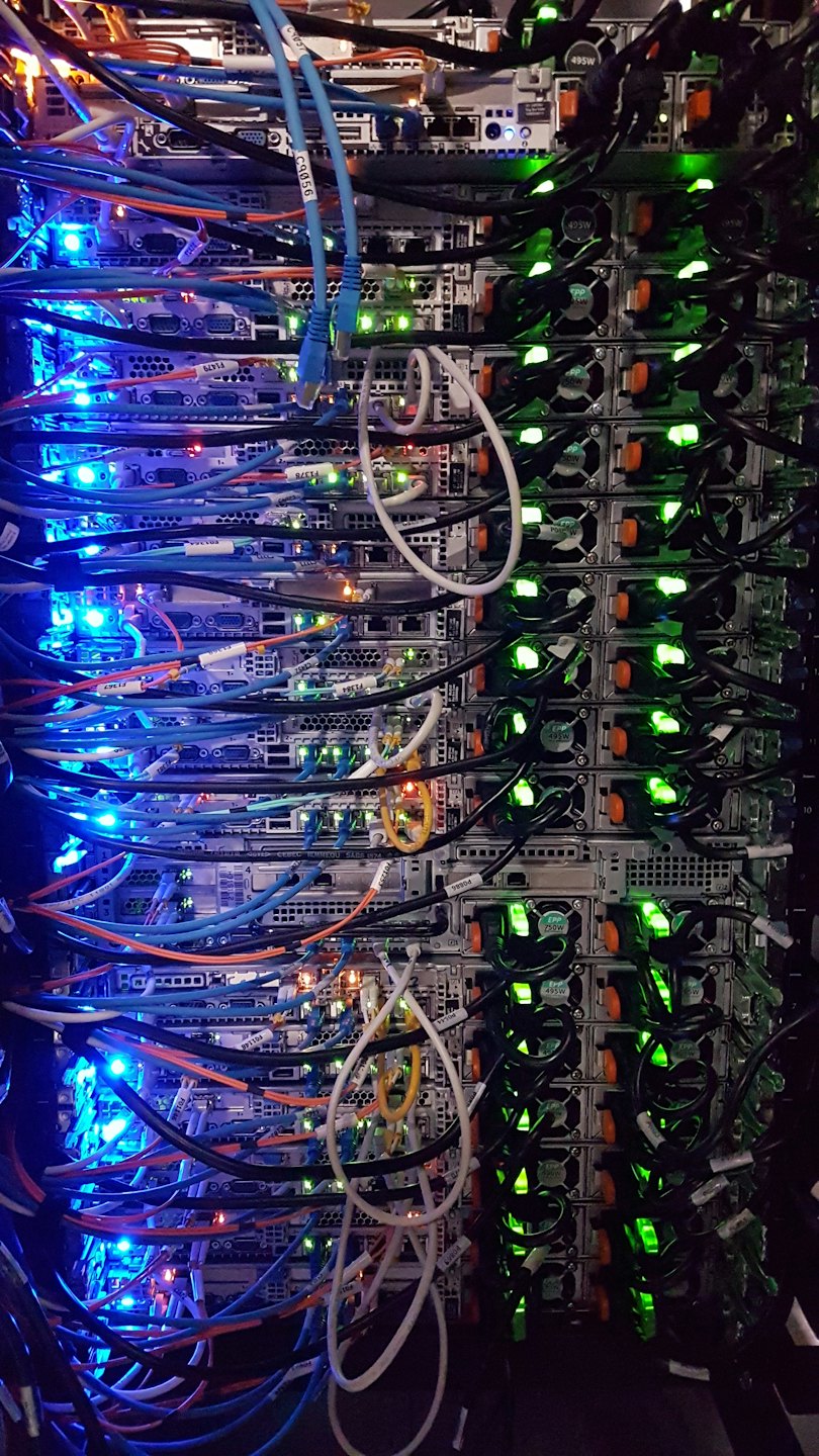 Rack di server con molti cavi colorati e luci lampeggianti.